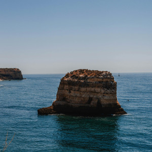 Stunning rock formation in the Algarve's deep blue waters under a clear sky.